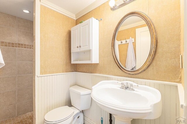 bathroom with ornamental molding, a wainscoted wall, a sink, and toilet