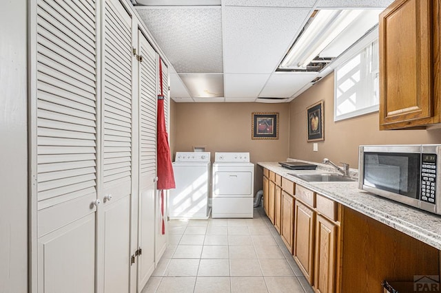 washroom featuring cabinet space, a sink, washing machine and clothes dryer, and light tile patterned floors