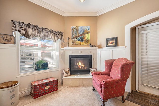 living area featuring ornamental molding, a tiled fireplace, and carpet flooring