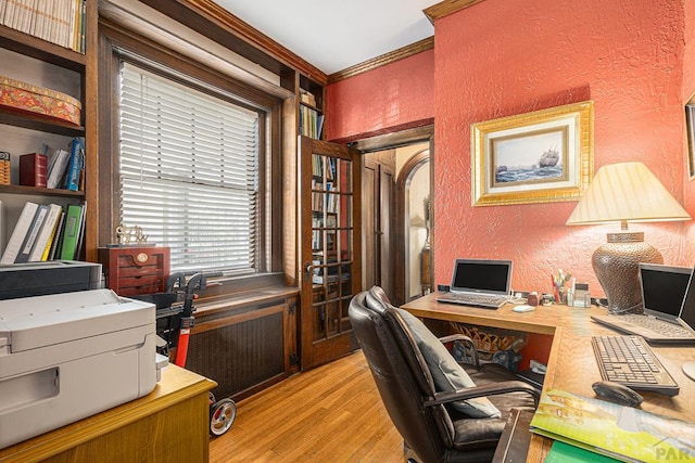 office area with light wood-style floors, a textured wall, and ornamental molding