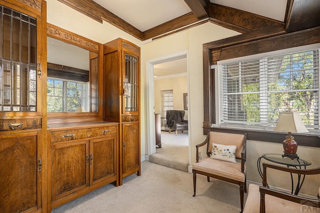 sitting room featuring crown molding, lofted ceiling with beams, and light colored carpet