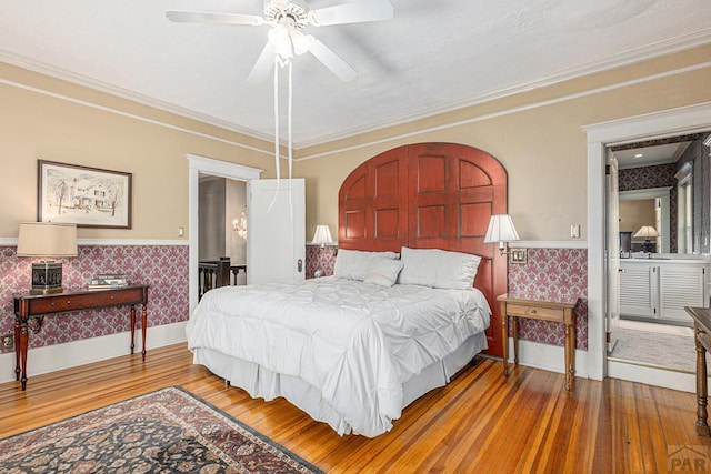 bedroom with wood finished floors, wainscoting, and wallpapered walls