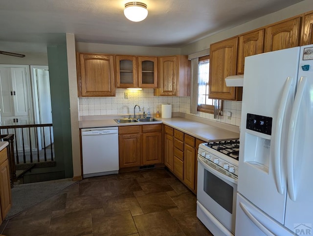 kitchen featuring glass insert cabinets, white appliances, light countertops, and a sink