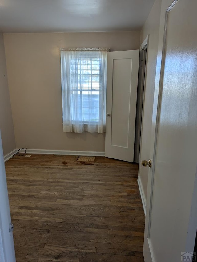 unfurnished bedroom featuring baseboards and dark wood finished floors