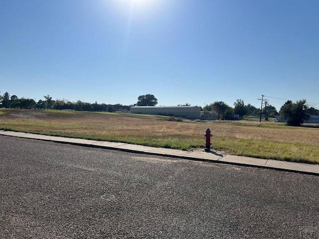 view of road with sidewalks, a rural view, and curbs