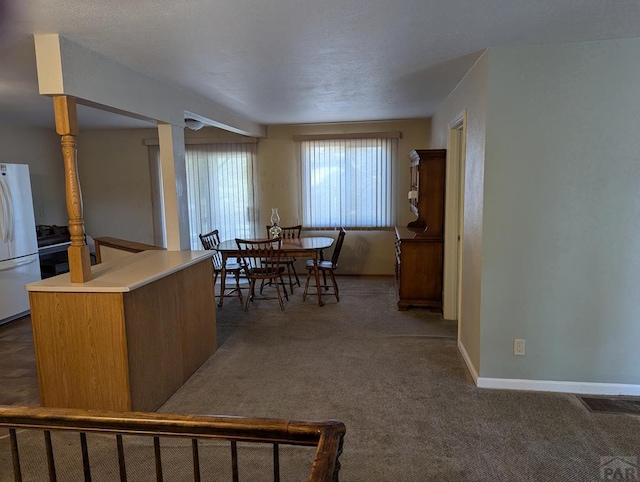 dining space featuring baseboards, visible vents, and dark carpet