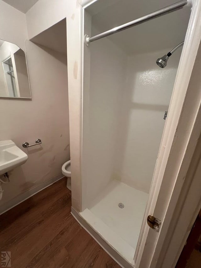 full bathroom featuring a shower stall, toilet, and wood finished floors