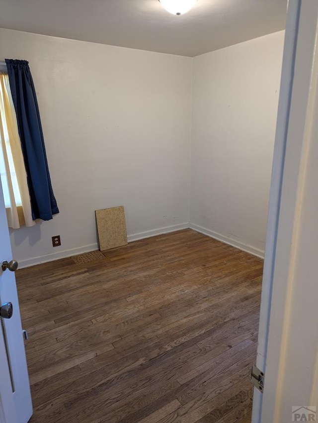 empty room with dark wood finished floors and baseboards