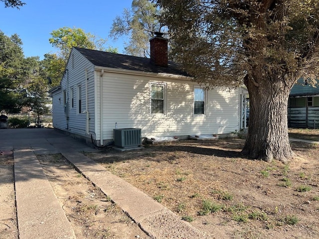 view of home's exterior featuring central air condition unit and a chimney