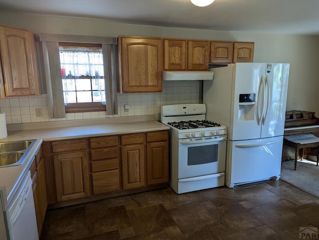 kitchen with white appliances, under cabinet range hood, stone finish floor, and light countertops