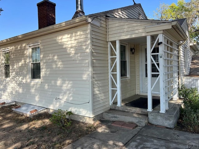 view of side of home with entry steps and a chimney