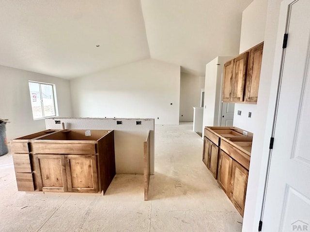 kitchen featuring lofted ceiling, a kitchen island, and brown cabinetry