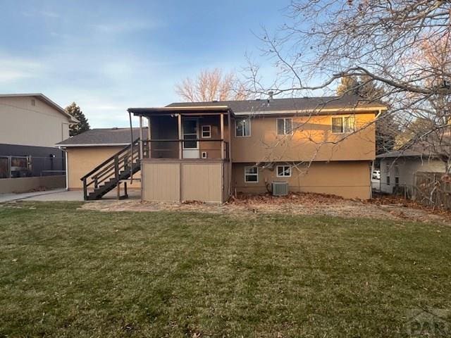 rear view of house with a sunroom, a lawn, central AC unit, and stairs