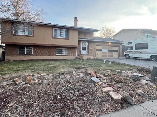 view of front of house with a garage, driveway, brick siding, and a chimney