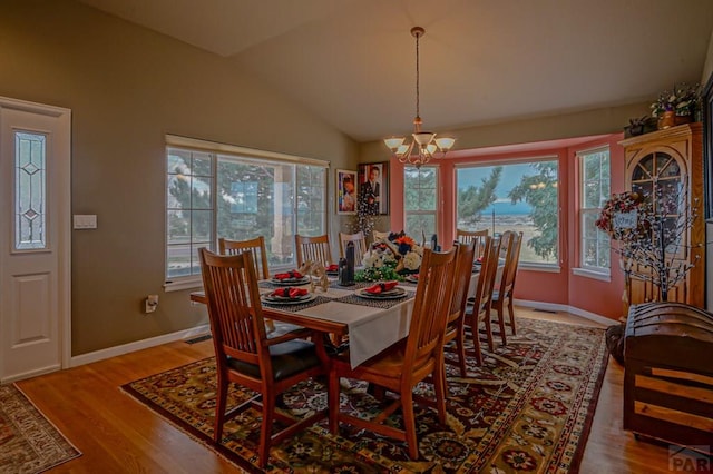 dining area with a wealth of natural light, lofted ceiling, a notable chandelier, and wood finished floors