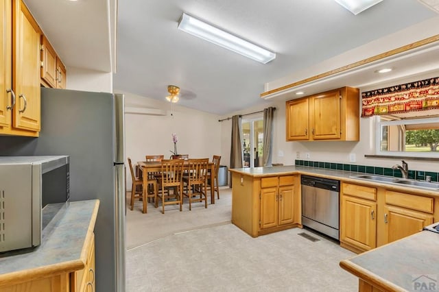 kitchen featuring visible vents, appliances with stainless steel finishes, a peninsula, light countertops, and a sink