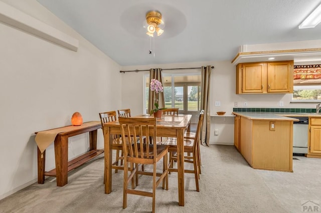 dining space with light carpet, ceiling fan, and baseboards