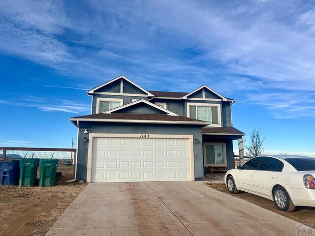 view of front of property with a shingled roof, concrete driveway, and stucco siding