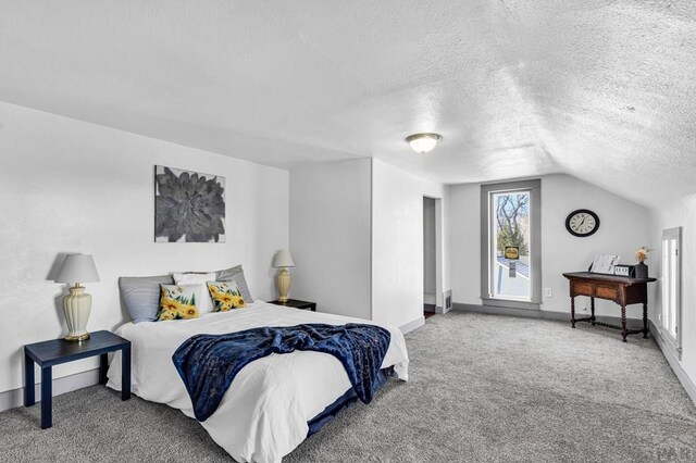 carpeted bedroom with vaulted ceiling, a textured ceiling, and baseboards