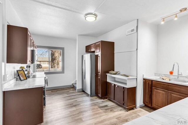 kitchen featuring stainless steel appliances, light countertops, visible vents, a sink, and light wood-type flooring