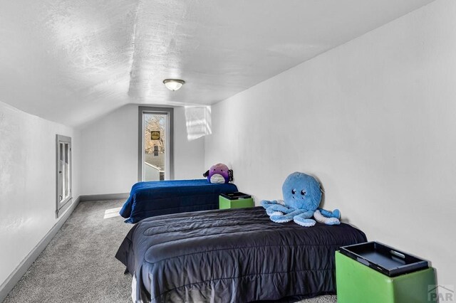 carpeted bedroom with baseboards, vaulted ceiling, and a textured ceiling