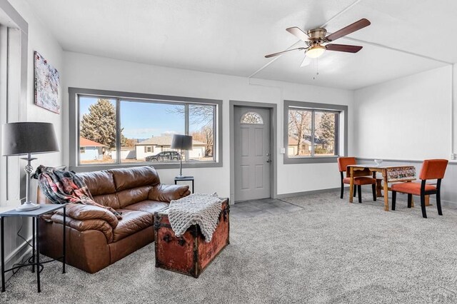 carpeted living room with a ceiling fan, a wealth of natural light, and baseboards