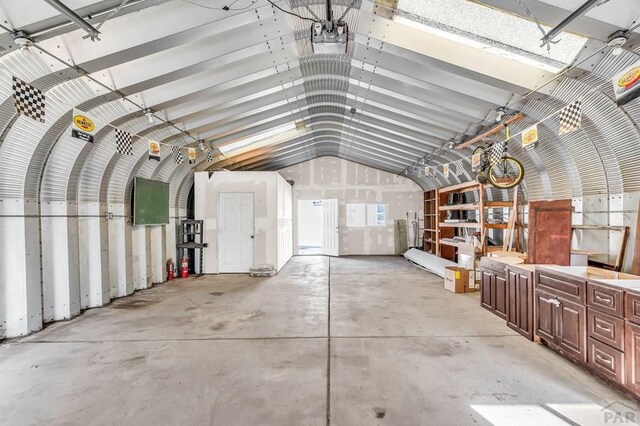 interior space featuring lofted ceiling, concrete floors, metal wall, and a garage