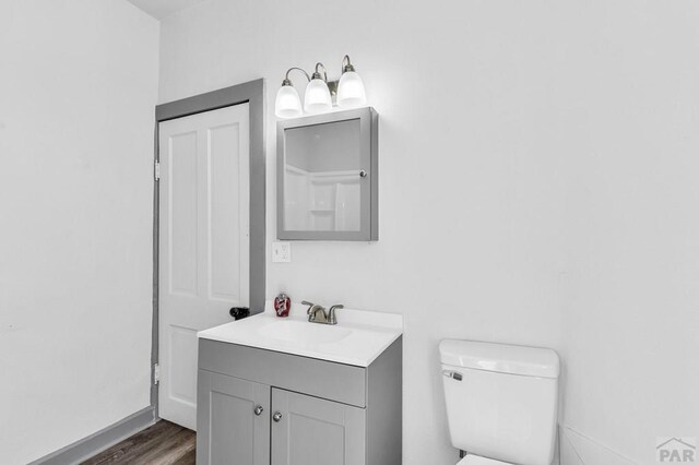 bathroom with toilet, wood finished floors, and vanity