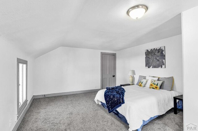 bedroom with lofted ceiling, baseboards, a textured ceiling, and light colored carpet