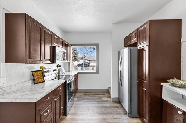 kitchen with appliances with stainless steel finishes, light countertops, light wood-style flooring, and dark brown cabinets