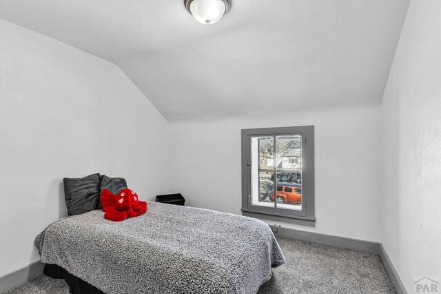 carpeted bedroom featuring baseboards and vaulted ceiling