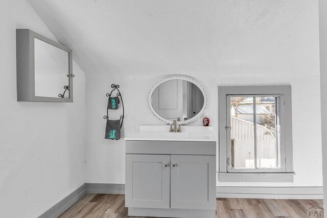 bathroom featuring lofted ceiling, vanity, baseboards, and wood finished floors