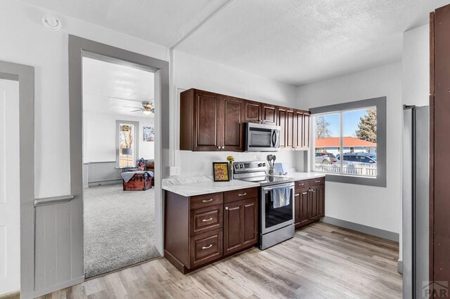 kitchen featuring appliances with stainless steel finishes, light wood-type flooring, a healthy amount of sunlight, and light countertops