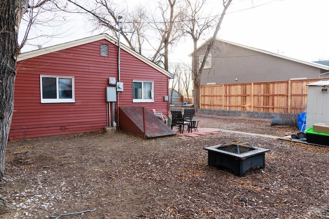 rear view of house with an outdoor fire pit and fence