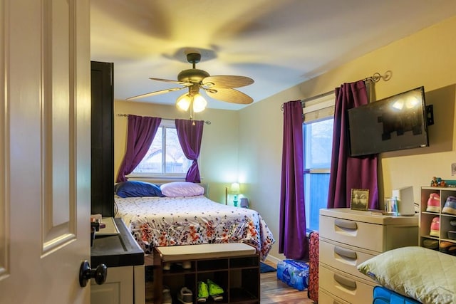 bedroom with multiple windows, a ceiling fan, and wood finished floors