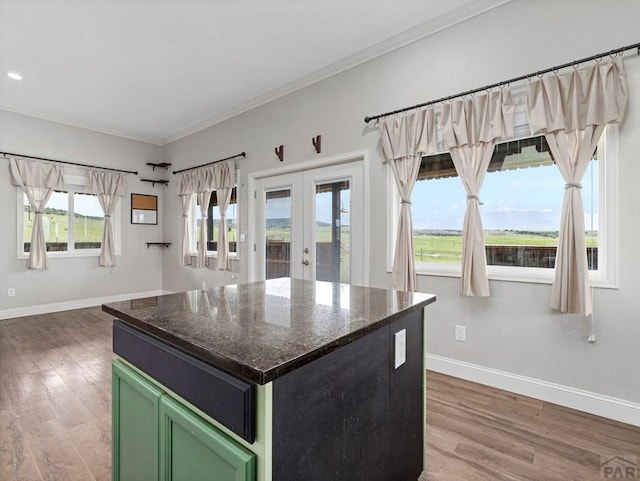 kitchen with baseboards, french doors, a center island, dark stone countertops, and green cabinetry