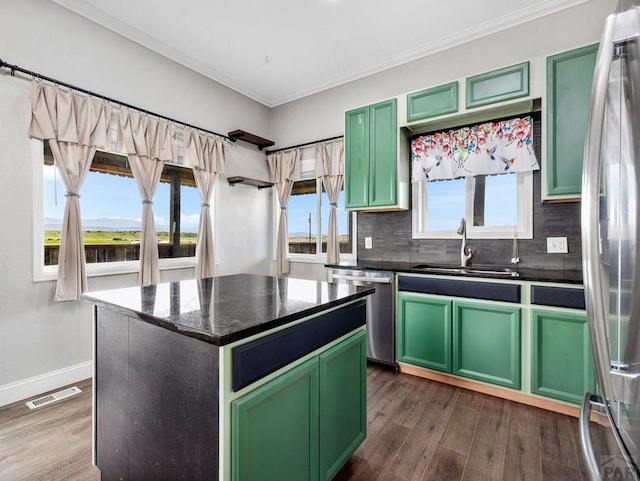 kitchen featuring visible vents, a kitchen island, a sink, stainless steel appliances, and green cabinetry