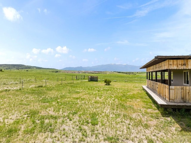 view of yard featuring an outbuilding, a rural view, an exterior structure, and a mountain view