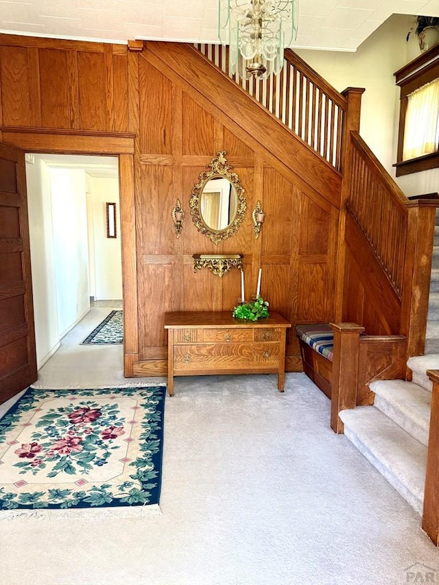 602 Belleview Ave, La Junta, CO 81050 - corridor with carpet floors, stairway, wood walls, and a chandelier