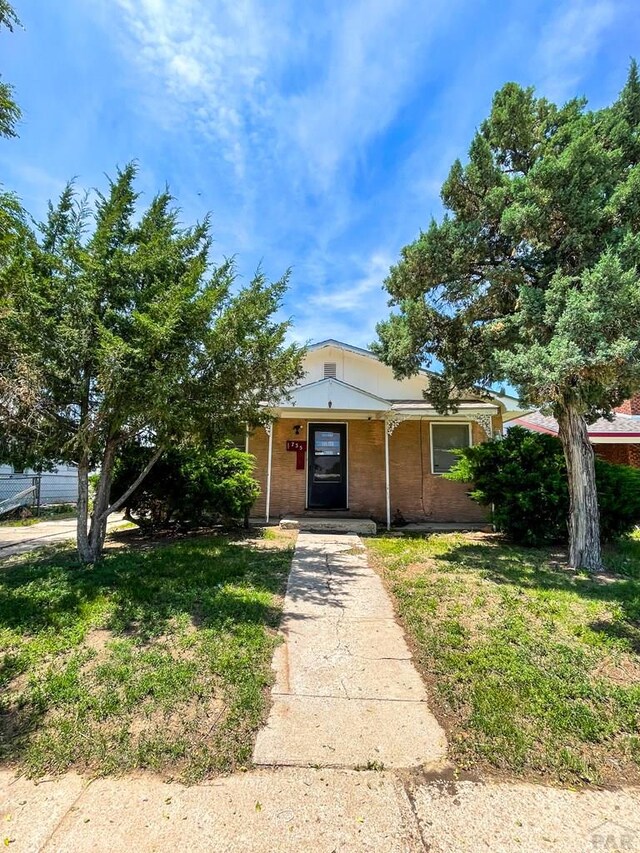 735 Poplar Ave, Las Animas, CO 81054 - view of front facade featuring covered porch, a front lawn, and brick siding