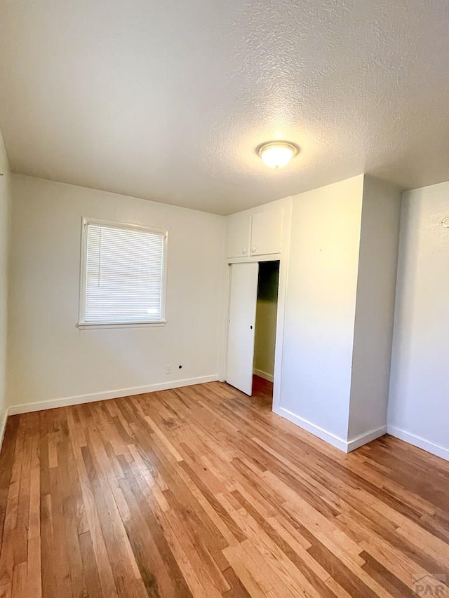 735 Poplar Ave, Las Animas, CO 81054 - unfurnished bedroom featuring light wood-style flooring, a textured ceiling, and a closet
