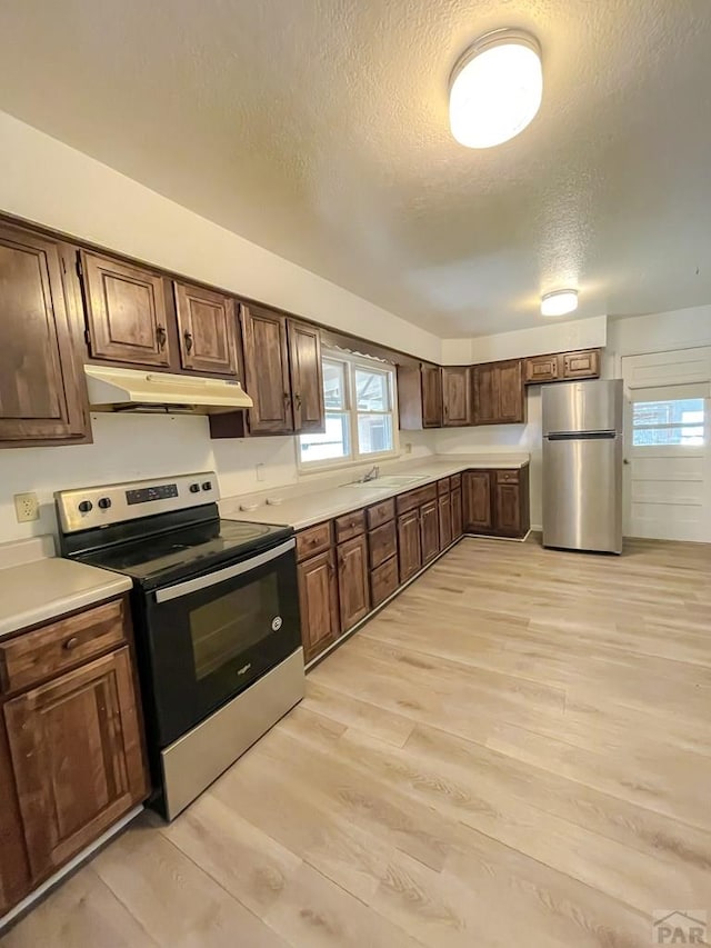 735 Poplar Ave, Las Animas, CO 81054 - kitchen featuring appliances with stainless steel finishes, under cabinet range hood, a textured ceiling, light wood finished floors, and light countertops