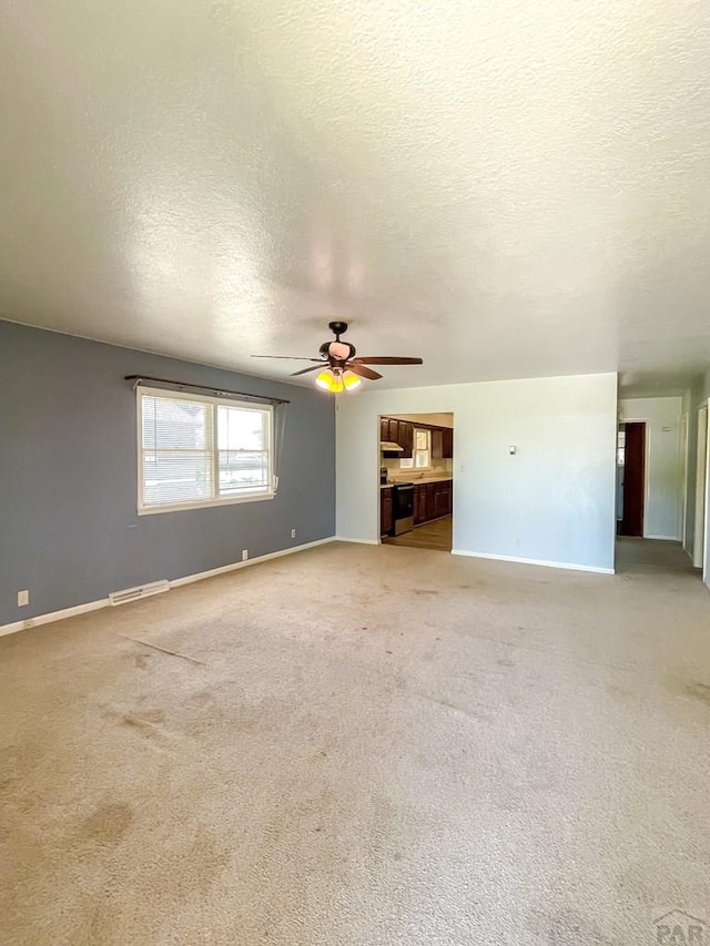 735 Poplar Ave, Las Animas, CO 81054 - unfurnished living room with a ceiling fan, a textured ceiling, and light colored carpet