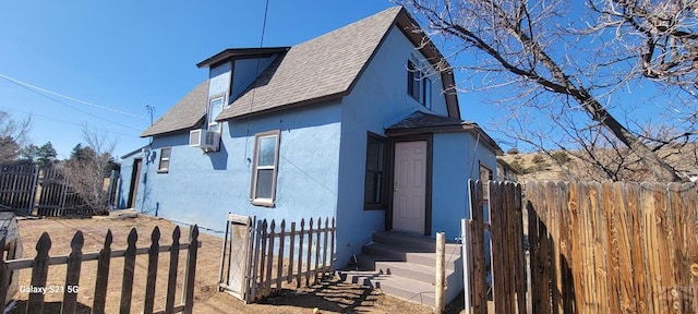 view of front of property featuring entry steps, roof with shingles, fence, and stucco siding