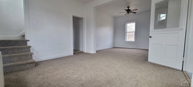 interior space featuring a ceiling fan, baseboards, and stairs