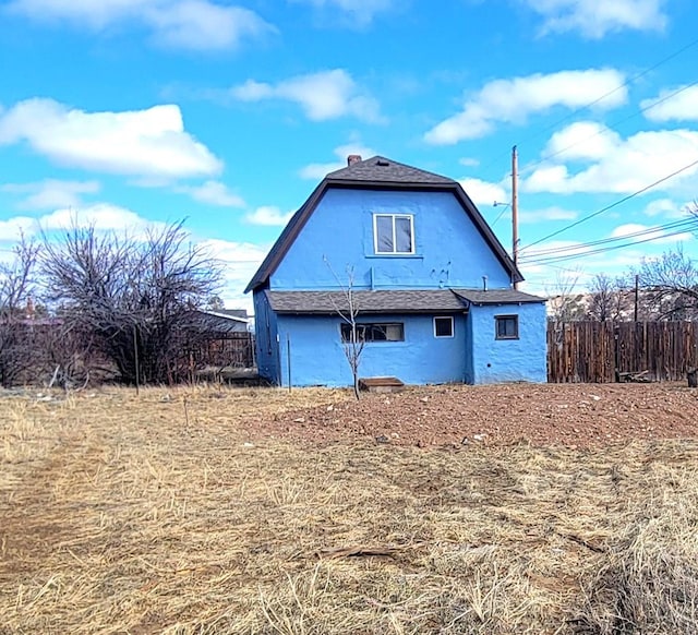 back of house featuring a yard, fence, and a gambrel roof