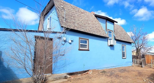 view of property exterior featuring roof with shingles, cooling unit, fence, and stucco siding