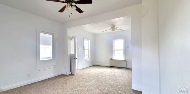 empty room with baseboards, ceiling fan, and light colored carpet