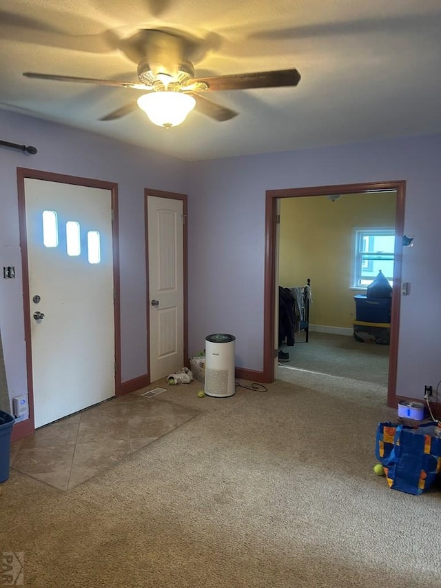 foyer featuring carpet floors, ceiling fan, and baseboards