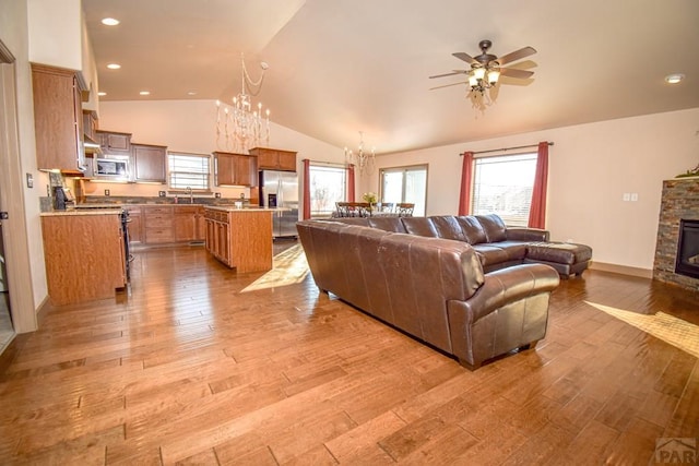 5707 Mark Twain Ln, Pueblo, CO 81008 - living room with a chandelier, ceiling fan, vaulted ceiling, light wood-style floors, and a fireplace